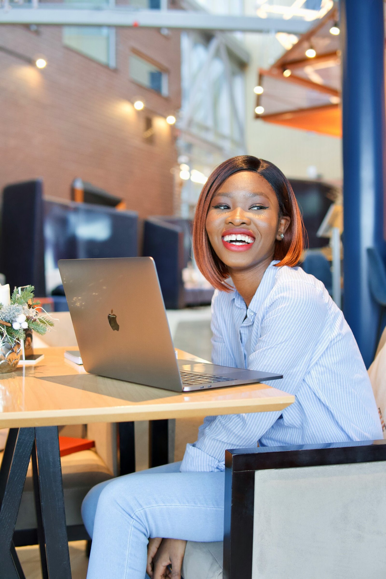 A happy young black woman in front of a laptop, smiling at the camera.